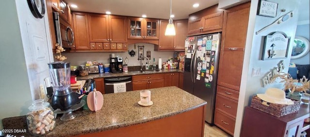 kitchen featuring light stone countertops, brown cabinetry, glass insert cabinets, and stainless steel appliances