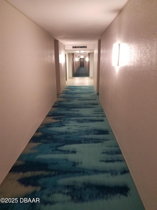 hallway featuring a textured wall and visible vents