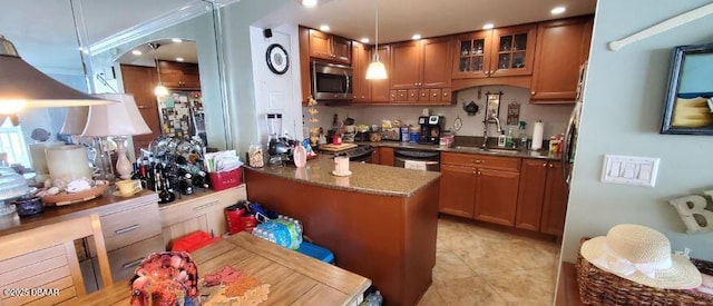 kitchen with brown cabinetry, glass insert cabinets, stainless steel appliances, and a sink