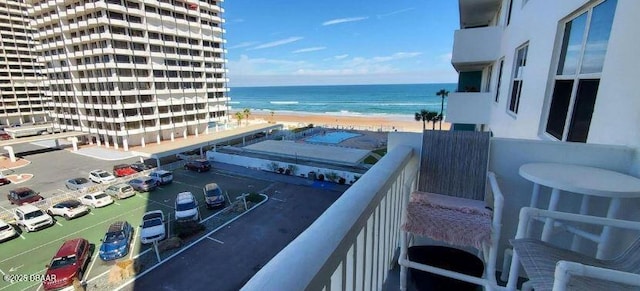 balcony with a water view and a view of the beach