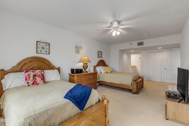 bedroom with light carpet, visible vents, a ceiling fan, ensuite bathroom, and a closet