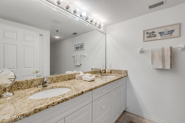 bathroom with visible vents, a sink, and double vanity