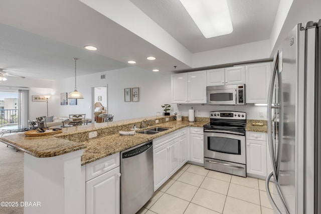 kitchen with a peninsula, white cabinetry, stainless steel appliances, and a sink