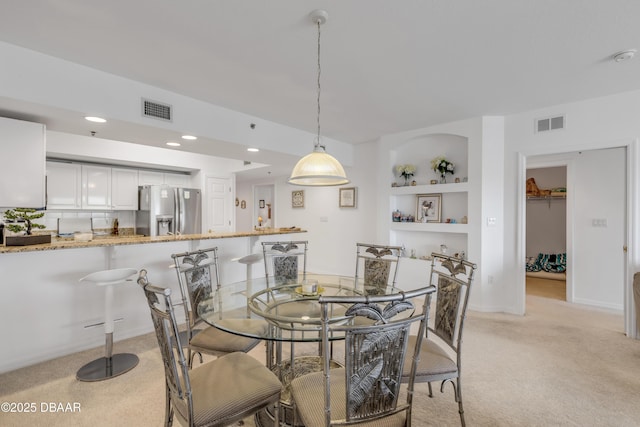 dining room with light carpet, built in shelves, visible vents, and recessed lighting