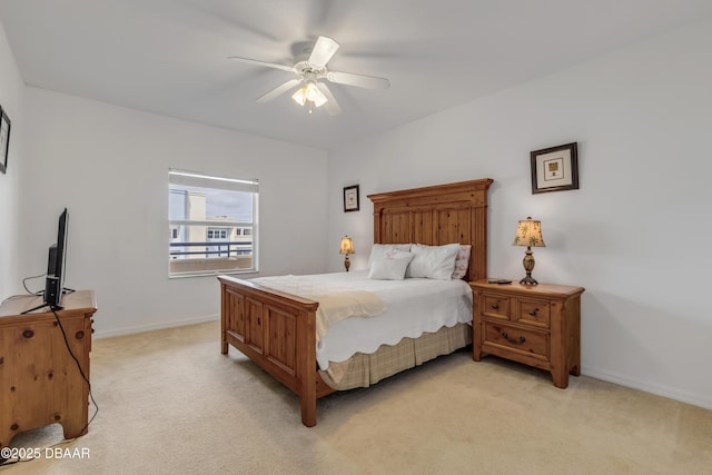 bedroom featuring light carpet, a ceiling fan, and baseboards