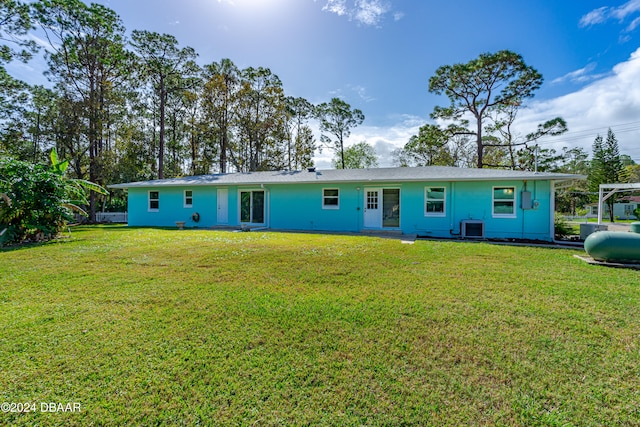 back of house with cooling unit and a yard