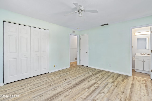 unfurnished bedroom with a closet, connected bathroom, light wood-type flooring, sink, and ceiling fan