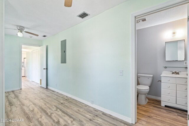 interior space featuring connected bathroom, light hardwood / wood-style flooring, electric panel, and ceiling fan