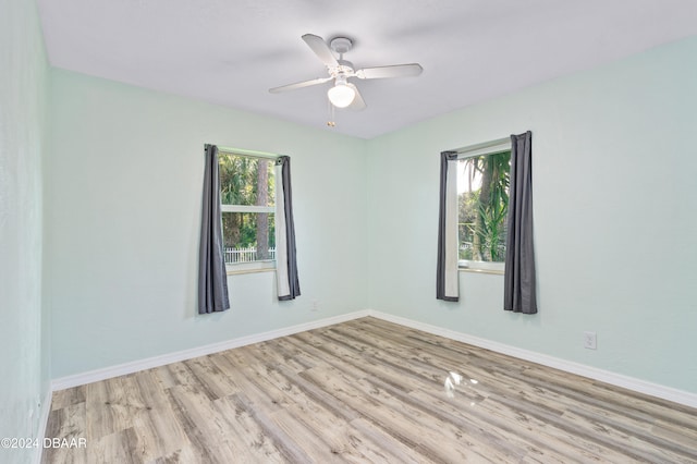 spare room with a wealth of natural light, ceiling fan, and light wood-type flooring