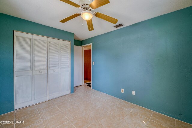 unfurnished bedroom with light tile patterned flooring, ceiling fan, and a closet