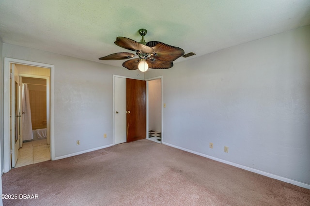 unfurnished bedroom with ensuite bathroom, light carpet, and ceiling fan