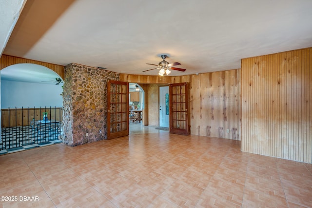 spare room featuring french doors, light parquet flooring, and wood walls