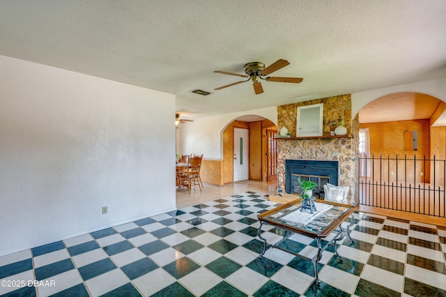 unfurnished living room with ceiling fan, a fireplace, and a textured ceiling