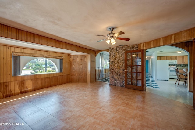 unfurnished room with a textured ceiling, ceiling fan, and wood walls