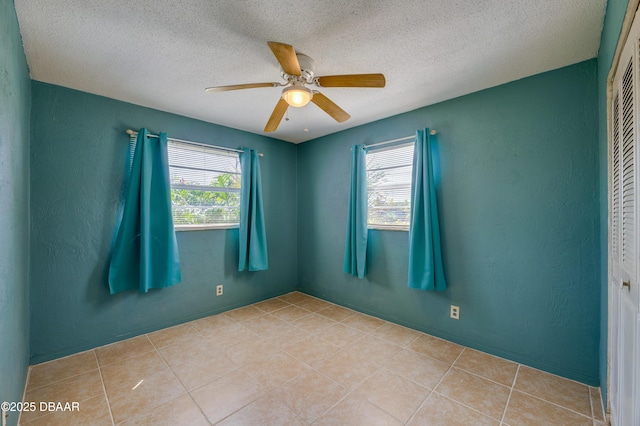 tiled spare room with a wealth of natural light, a textured ceiling, and ceiling fan