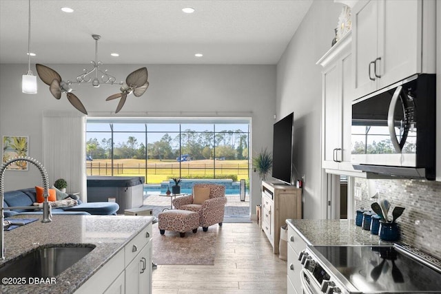 kitchen featuring white cabinets, light stone counters, sink, and stainless steel electric stove