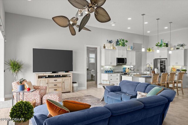 living room with sink, ceiling fan, a high ceiling, and light hardwood / wood-style flooring