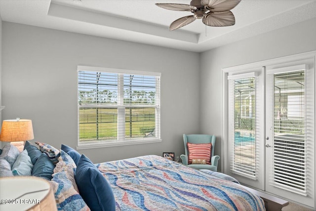 bedroom featuring access to exterior, a raised ceiling, and ceiling fan