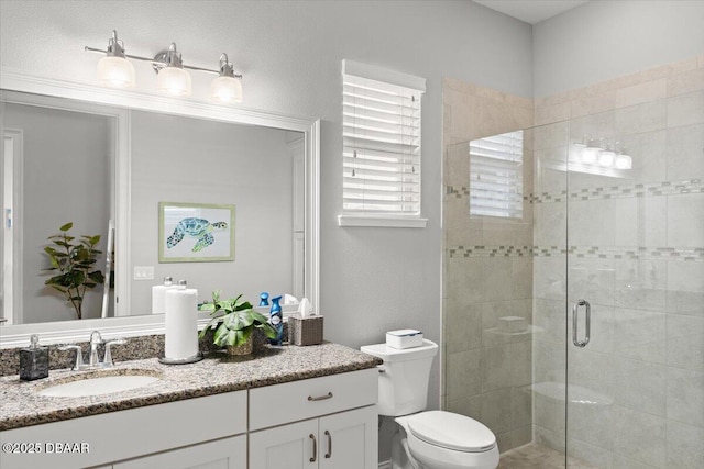 bathroom featuring a shower with shower door, toilet, and vanity