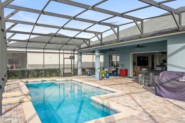 view of swimming pool with glass enclosure, a patio, and ceiling fan