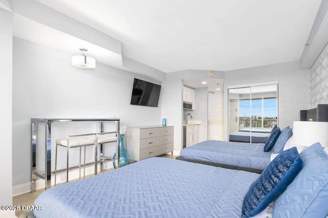 bedroom featuring baseboards, light wood-style floors, and a sink