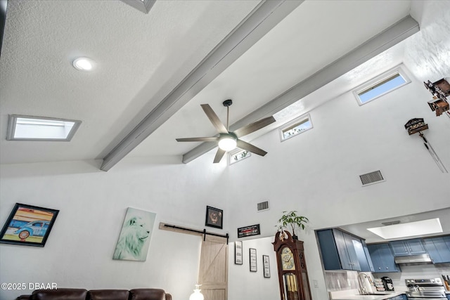 details featuring a barn door, beamed ceiling, ceiling fan, a textured ceiling, and stainless steel range with electric cooktop