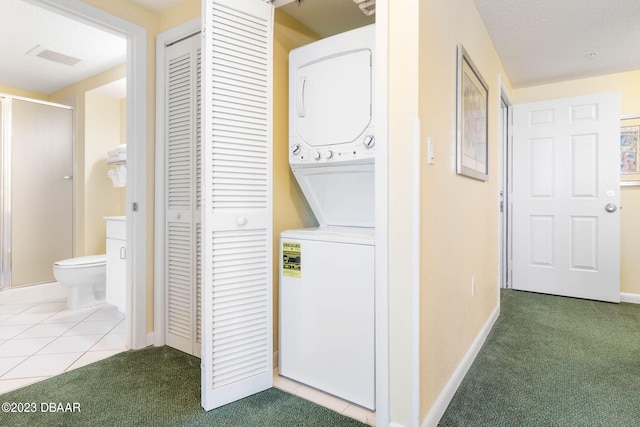 clothes washing area with stacked washer and clothes dryer and carpet