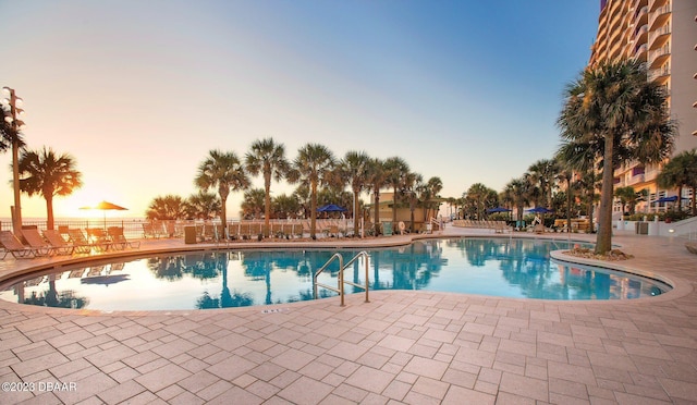 pool at dusk featuring a patio