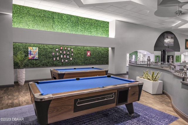 rec room with hardwood / wood-style floors, a towering ceiling, ceiling fan, and billiards