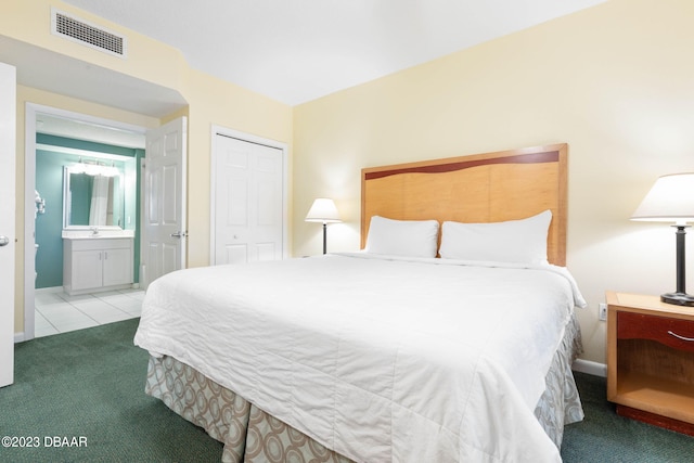 carpeted bedroom with ensuite bathroom and a closet