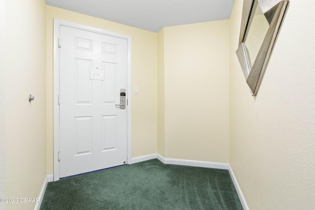 entryway with dark colored carpet and a textured ceiling