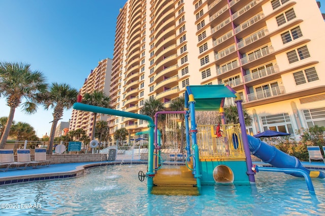 view of playground with pool water feature and a community pool