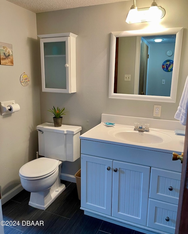 bathroom featuring toilet, vanity, a textured ceiling, and tile patterned flooring