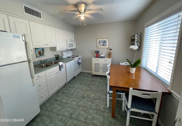 kitchen featuring white cabinetry, dark tile patterned flooring, sink, white appliances, and ceiling fan