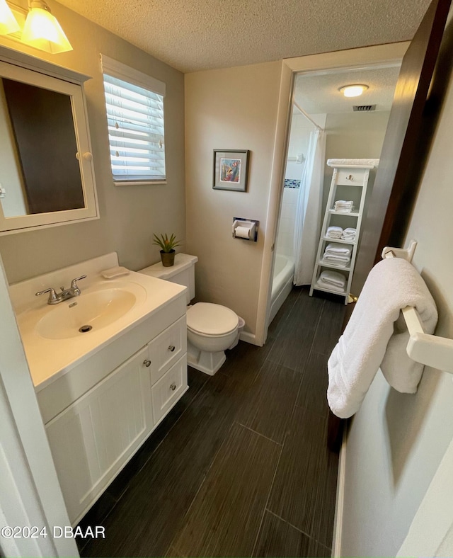 full bathroom featuring hardwood / wood-style floors, a textured ceiling, toilet, and vanity