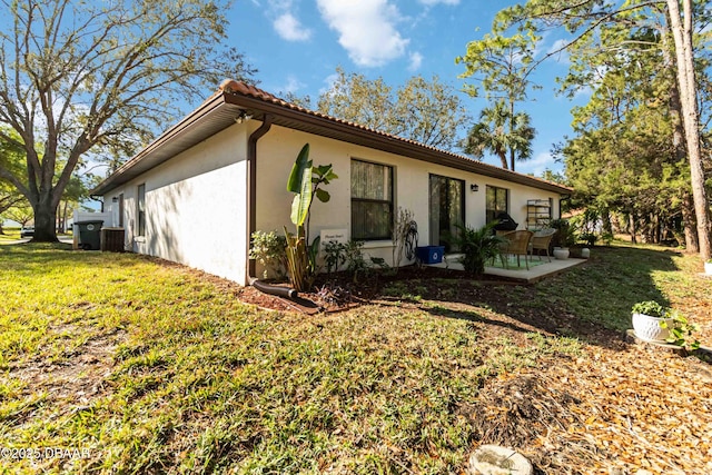 back of property with a patio area, stucco siding, a tile roof, and a yard