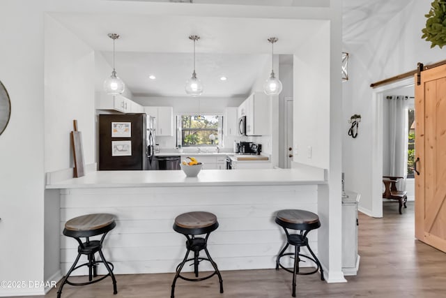 kitchen with a barn door, refrigerator with ice dispenser, dishwashing machine, wood finished floors, and range