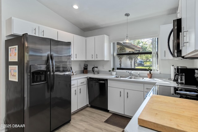 kitchen with black appliances, a sink, white cabinetry, light countertops, and vaulted ceiling