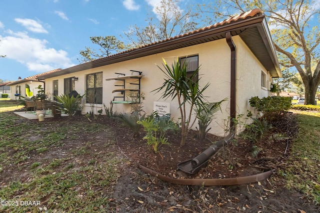 exterior space featuring stucco siding and a tiled roof