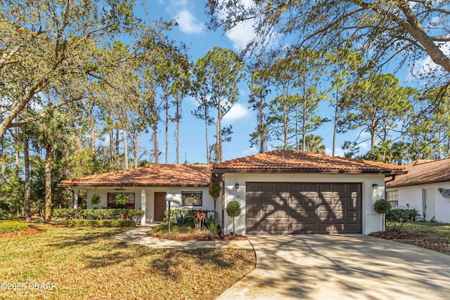 view of front facade with stucco siding, a tile roof, concrete driveway, a front yard, and a garage