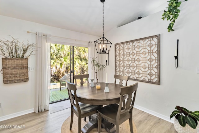 dining room with light wood finished floors, a chandelier, and baseboards