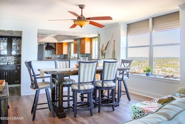 dining area featuring hardwood / wood-style flooring, ceiling fan, ornamental molding, and sink