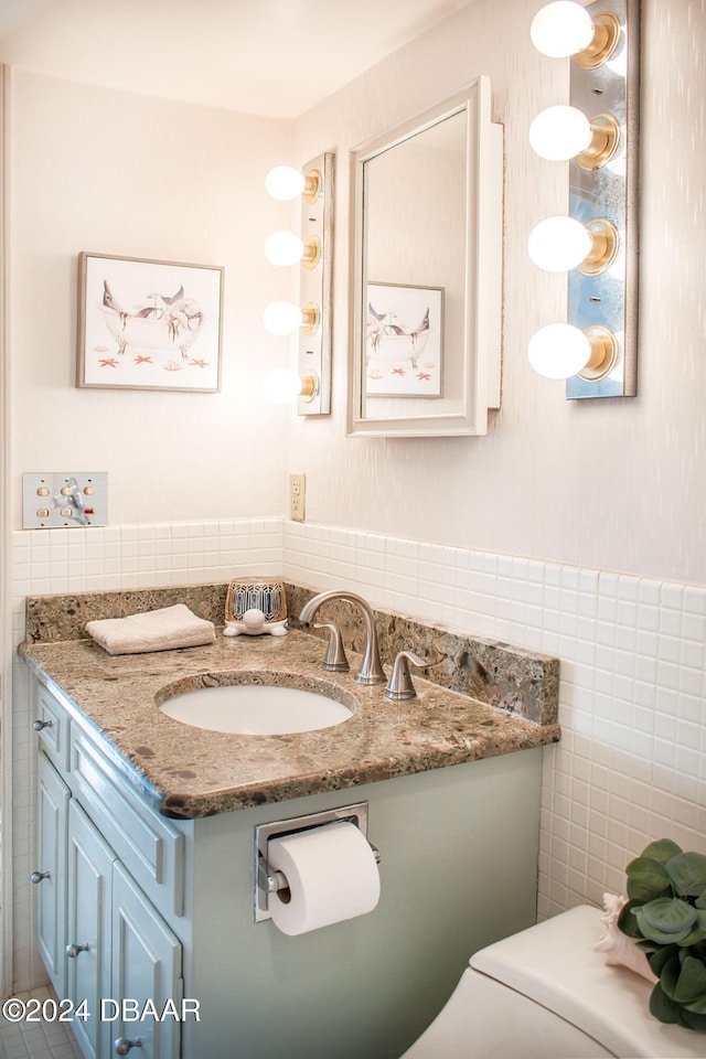 bathroom with vanity, toilet, and tile walls