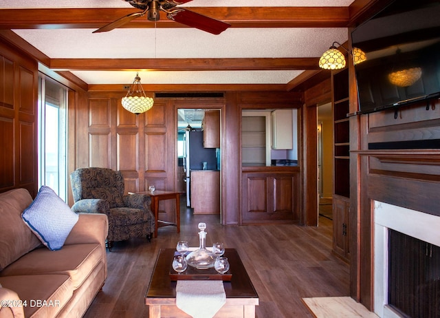 living room featuring wood walls, beam ceiling, and dark wood-type flooring