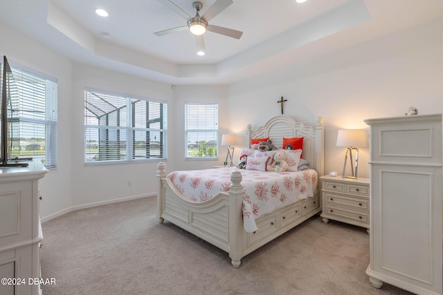 bedroom featuring multiple windows, light carpet, ceiling fan, and a raised ceiling