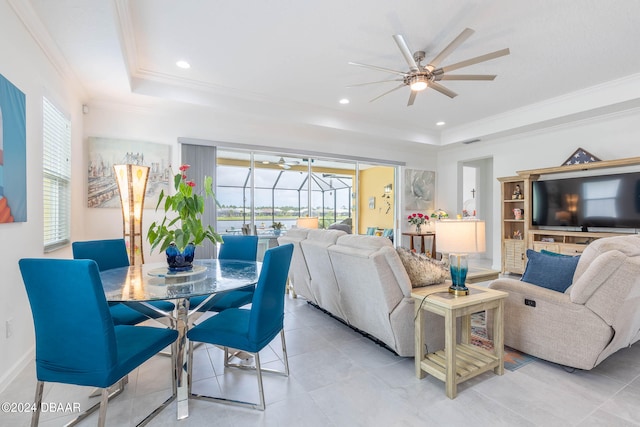 tiled living room featuring ceiling fan, a tray ceiling, a healthy amount of sunlight, and crown molding