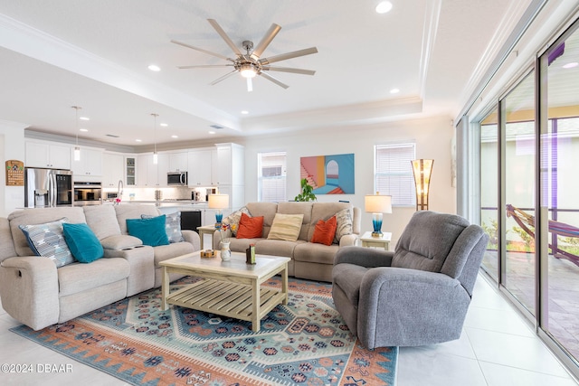 tiled living room featuring ornamental molding, a tray ceiling, and ceiling fan