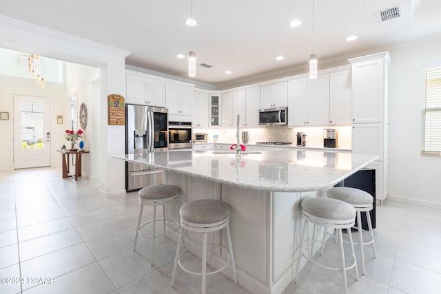 kitchen featuring ornamental molding, stainless steel appliances, white cabinetry, pendant lighting, and a spacious island