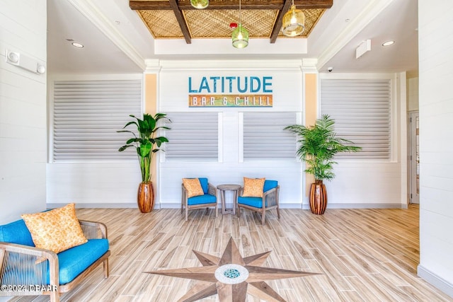 living area with wood walls, a tray ceiling, wood-type flooring, and crown molding