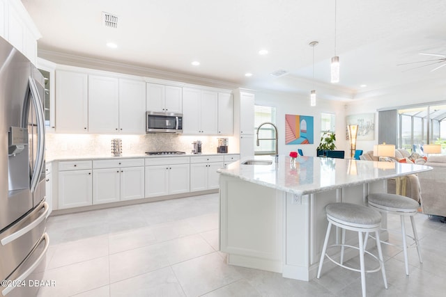 kitchen with white cabinets, hanging light fixtures, sink, an island with sink, and appliances with stainless steel finishes